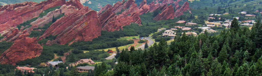 red rocks jut up next to a forested road and neighborhood.