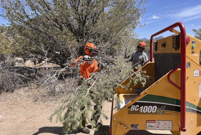 Using a chipper to turn downed trees and thinned branches into mulch is one way to create more defensible space around a home or building. 