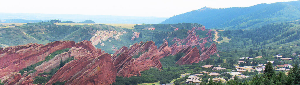 group of homes in front of giant red rocks and forested mountains