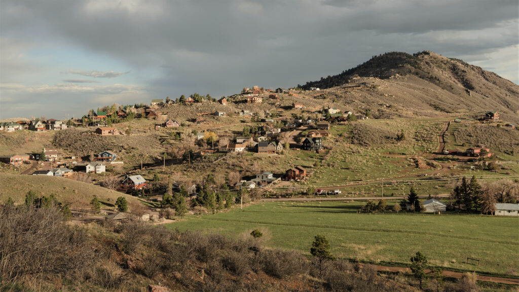 A community of homes intersects with hills, shrubs, grasses and trees in the Colorado wildland-urban interface