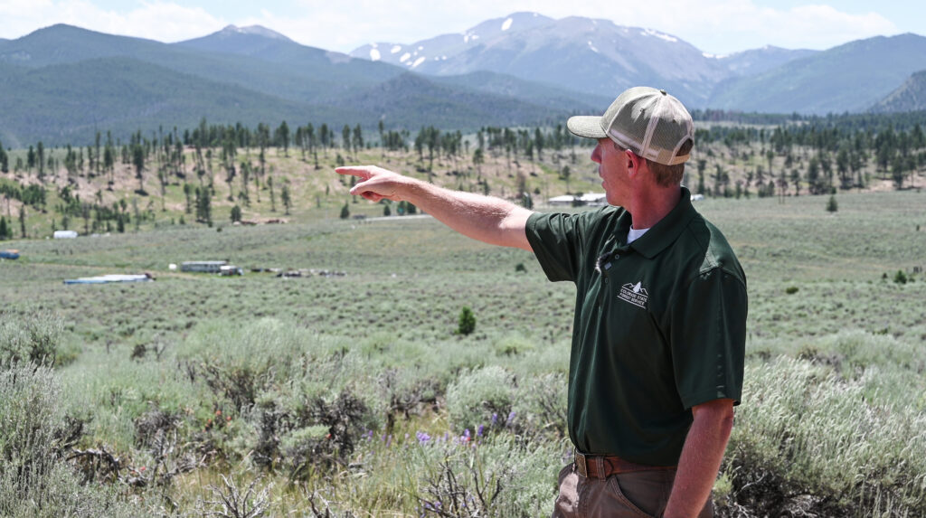 Adam Moore points to a ridgeline across Poncha Pass that has been impacted by insects